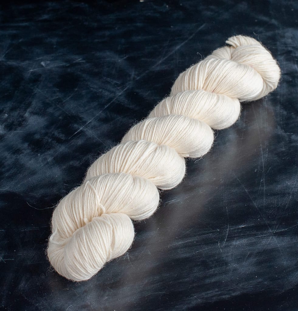 A skein of undyed merino fingering yarn 