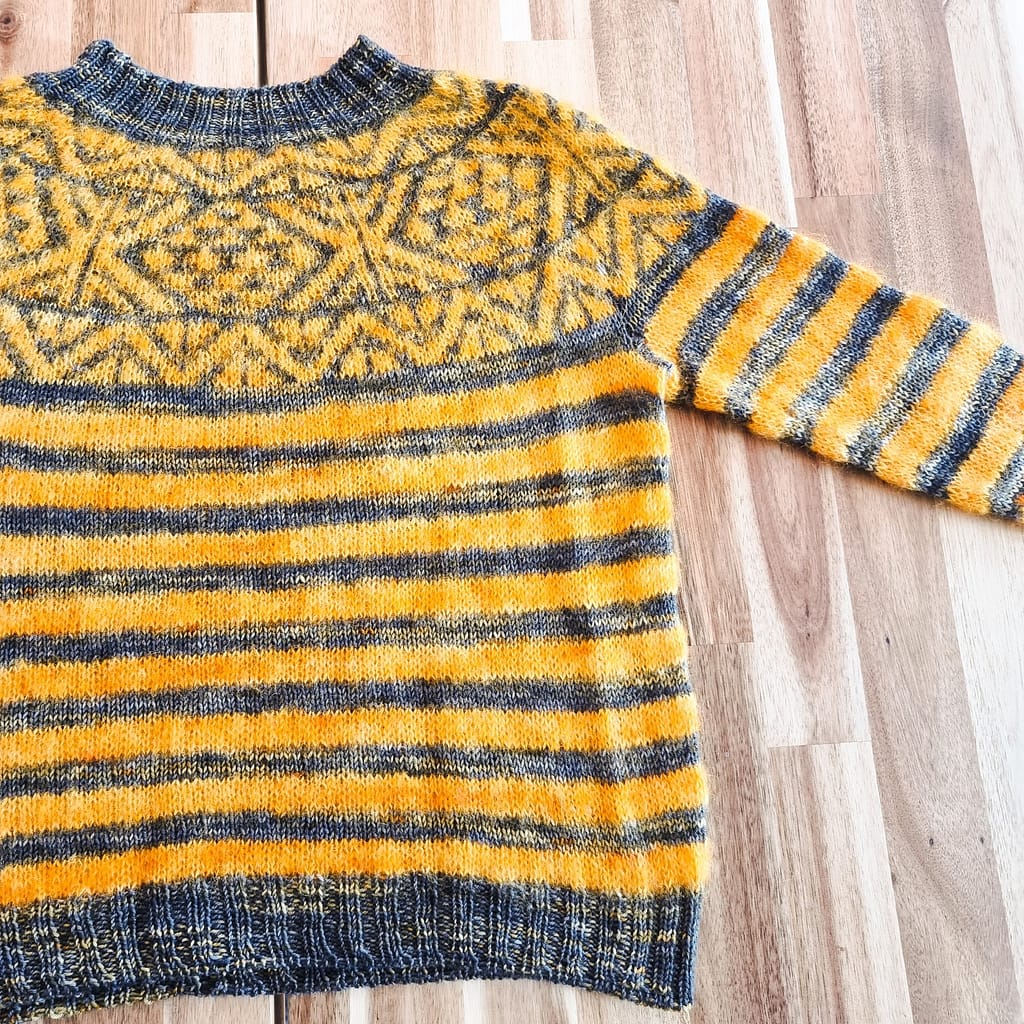 A red and grey striped sweater with colorwork around the toke