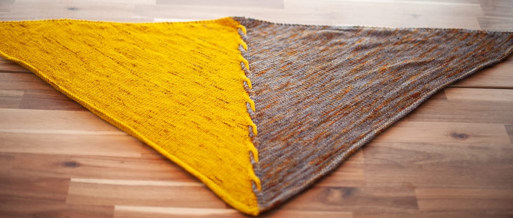 The Edge of Winter Shawl: a triangular shawl laying flat on a table.