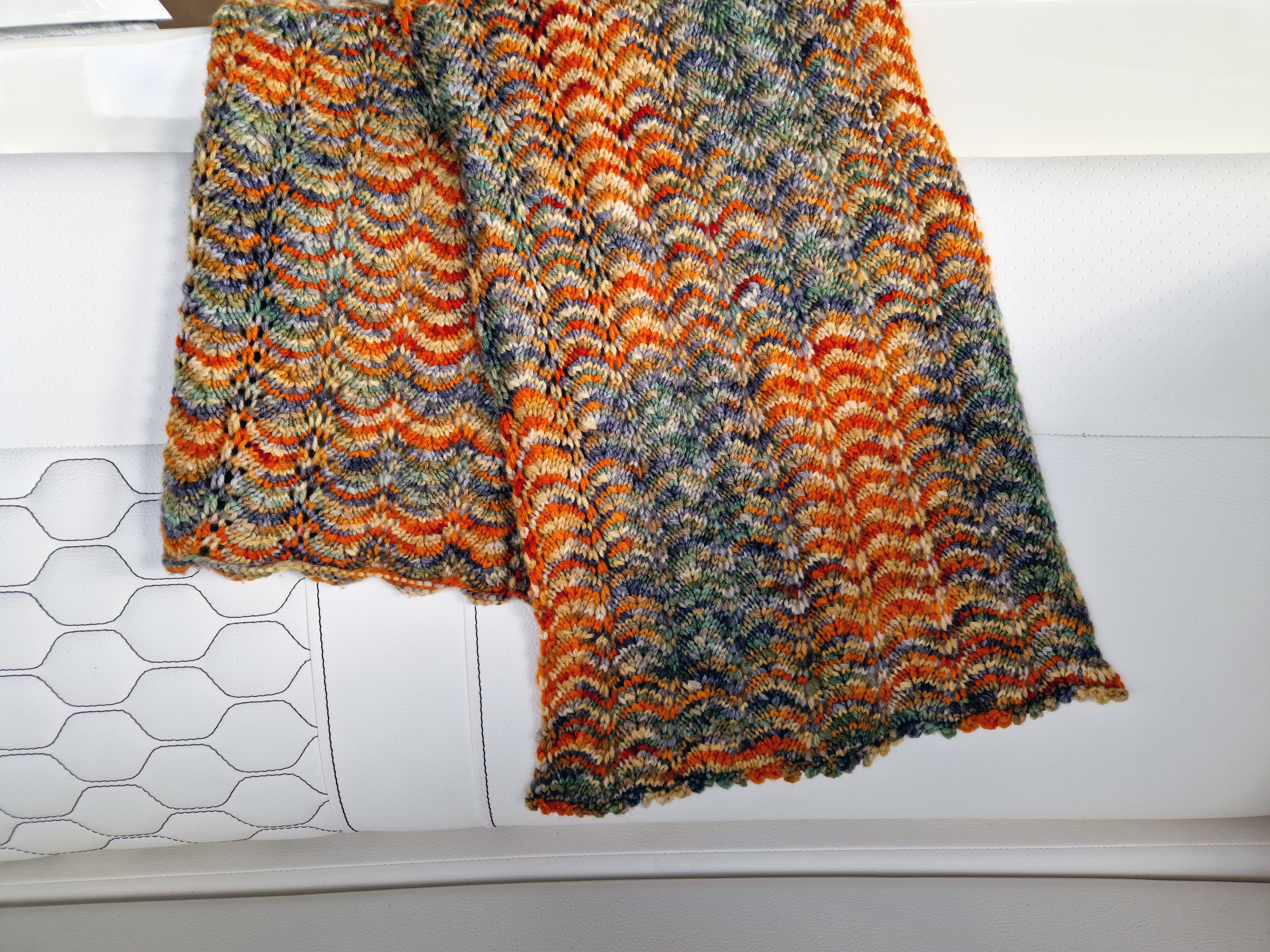 Close-up of the end of a orange and green hand-knit scarf