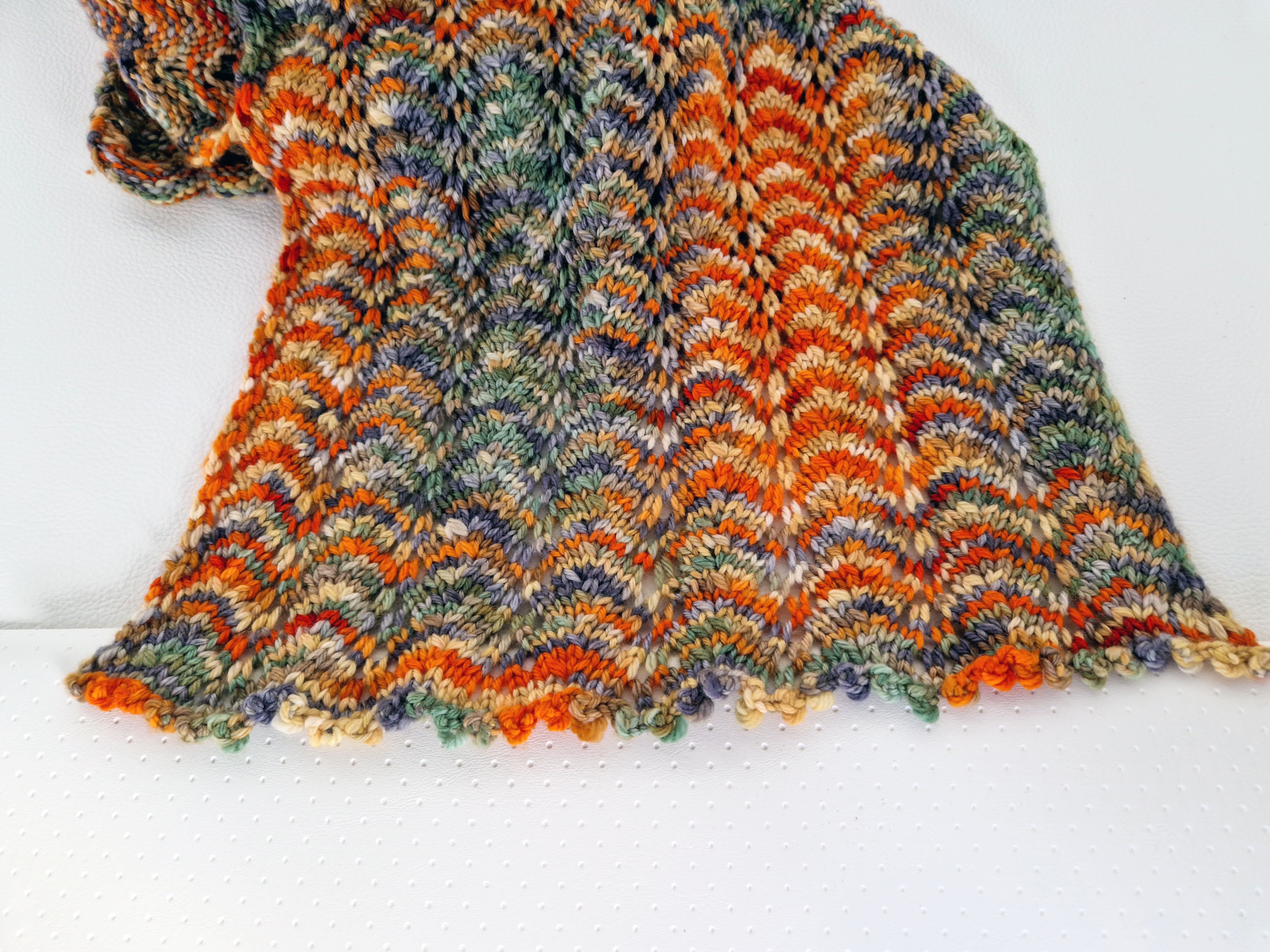 Close-up of the end of a orange and green hand-knit scarf