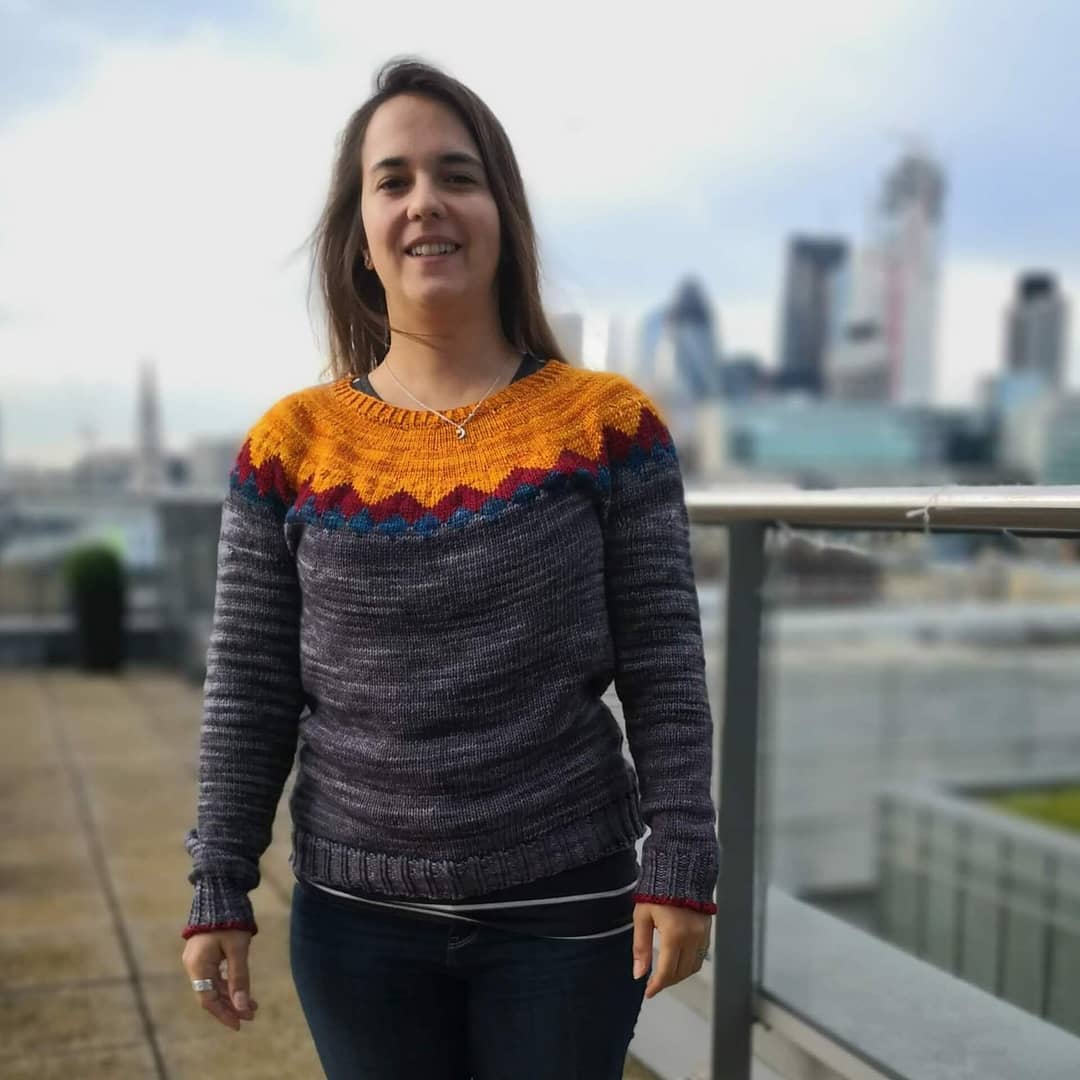 Woman wearing a colored woolen sweater, with the London skyline in the background