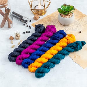 Five small skeins of yarn in black, magenta, blue, yellow and blue-green