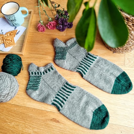 A pair of grey shortie socks with green toes and heels