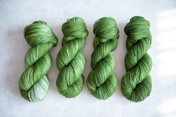 Four skeins of yarn in varying shades of green