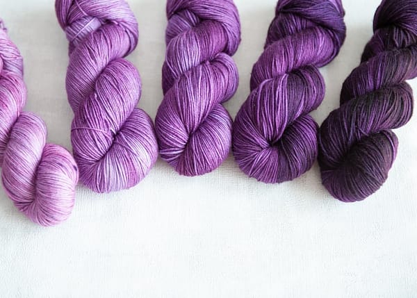 Five skeins of yarn in varying shades of purple