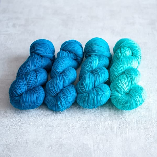 Four skeins of yarn in varying shades of blue