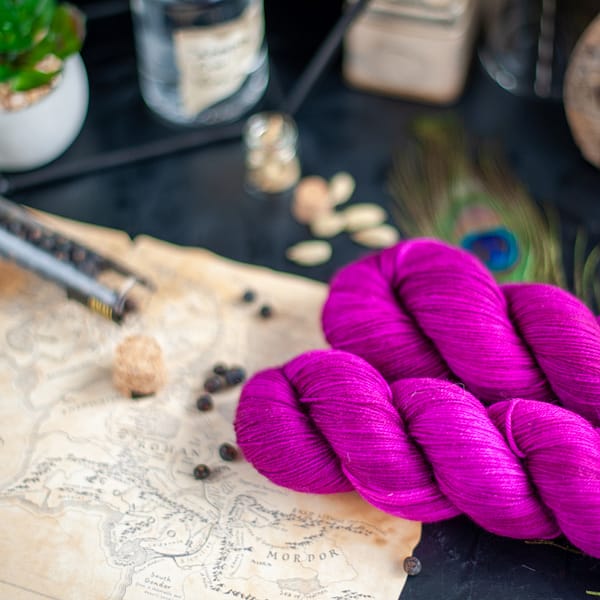 two skeins of magenta yarn laying on top of an old school map