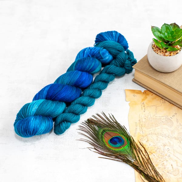 A skein of green and blue yarn and a blue mini-skein 