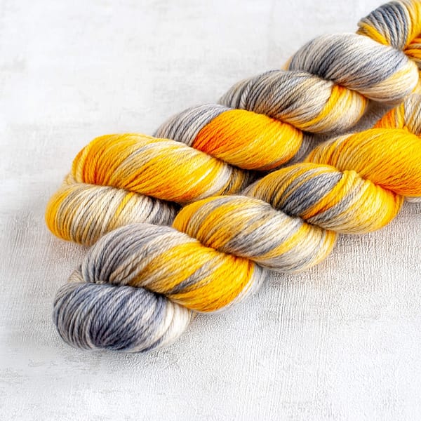 two skeins of grey and yellow yarn in DK weight laying next to each other