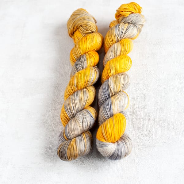 two skeins of grey and yellow yarn laying next to each other