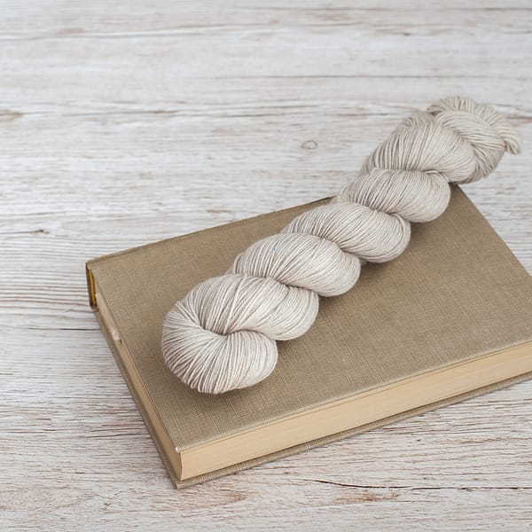 A skein of yarn in the color Pebbles on top of a book