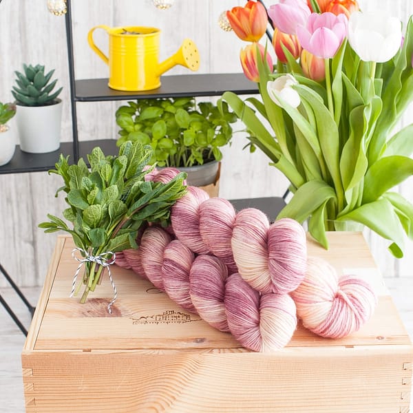 Three skeins of pink and cream yarn with some tulips