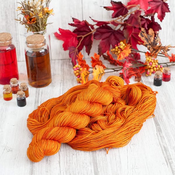 A skein of orange yarn laying on top of another open skein of yarn