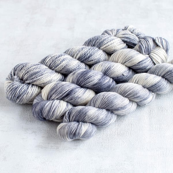 three skeins of light grey and white yarn