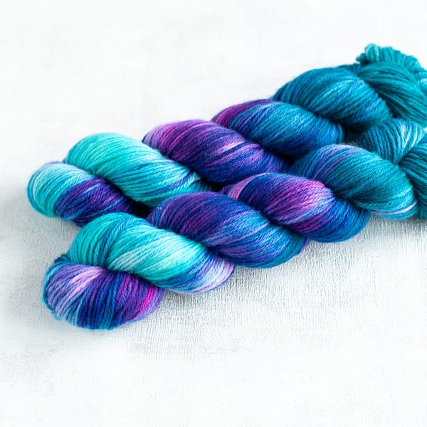 two skeins of DK weight blue, turquoise, green, and purple yarn