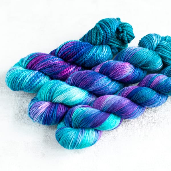 three skeins of blue, turquoise, green, and purple yarn
