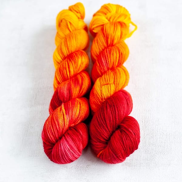 two skeins of DK weight red, orange, and yellow yarn
