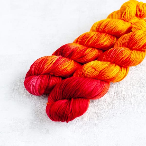 two skeins of DK weight red, orange, and yellow yarn