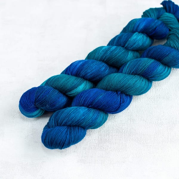 two fingering weight skeins of blue and green yarn