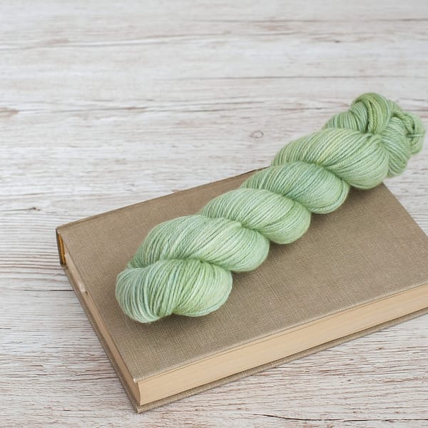 A skein of pale green yarn laying on top of a book