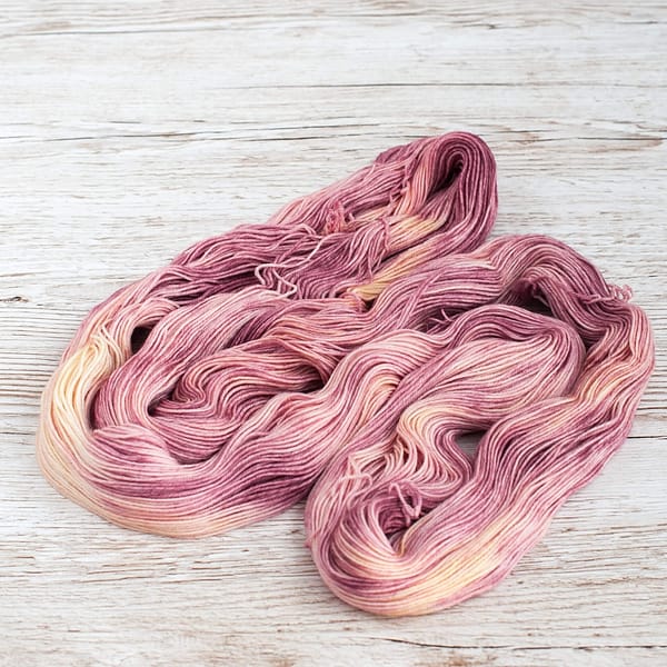 A skein of pink and cream yarn unwound and laid flat