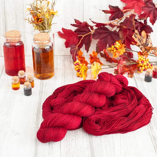 A skein of red yarn laying on top of another open skein of yarn