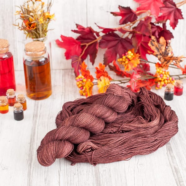 A skein of chocolate brown yarn laying on top of another open skein of yarn