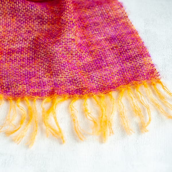 close-up on the fringe of a woven mohair shawl in purple and golden yellow