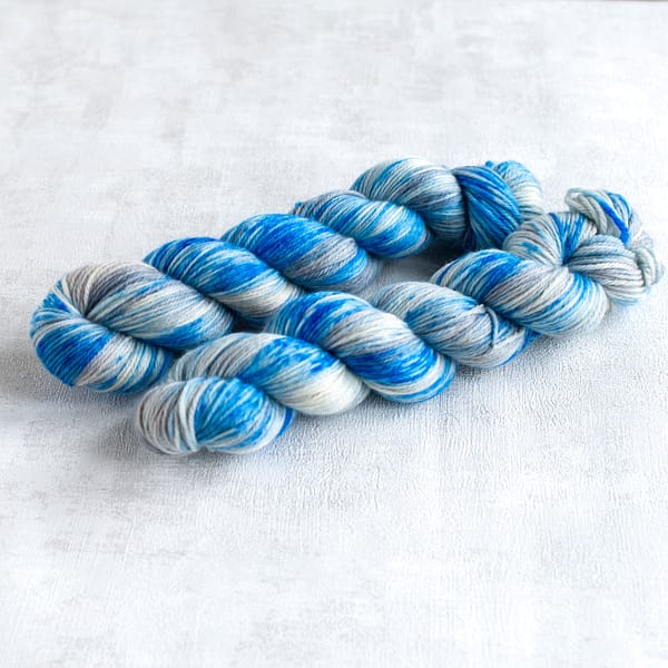 two skeins of DK weight silver yarn with blue speckles