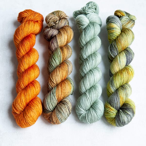 Four skeins in the following colorways: Heilan Coo (orange), Barrowland Ballroom (variegated), Portree Harbour (pale blue-green), Kilchurn Castle (green and grey with golden speckles)
