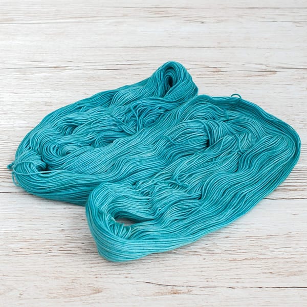 A pastel green-blue skein of yarn unwound and laid flat