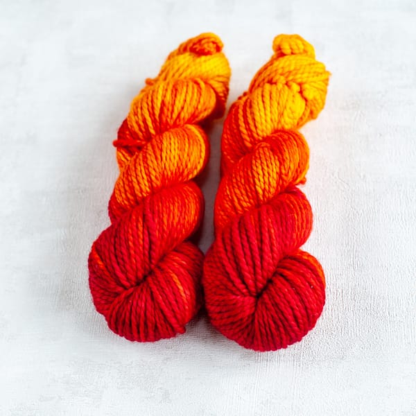 two skeins of chunky weight red, orange, and yellow yarn
