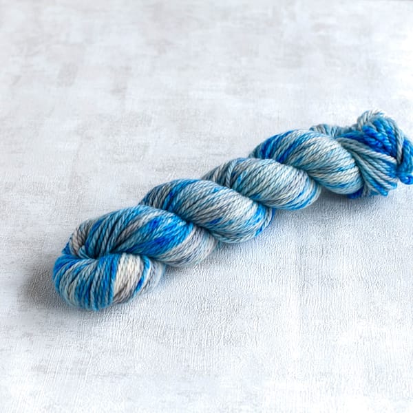 one skein of chunky weight silver yarn with blue speckles