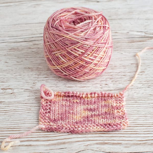 A swatch and cake of pink and cream yarn