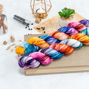 two skeins of multi-colored yarn laying on top of a book 