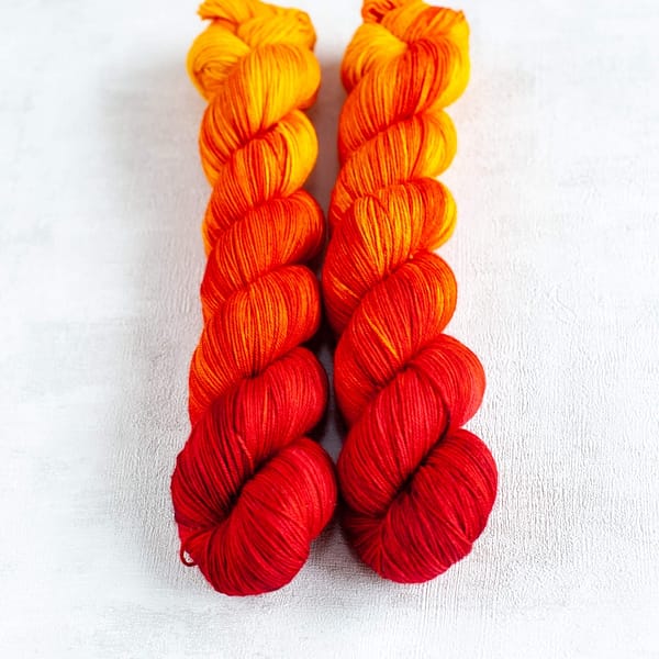 two skeins of fingering weight red, orange, and yellow yarn