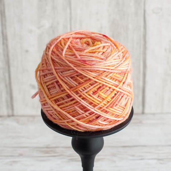 A skein of yarn in the color Peach Sorbet wound into a cake