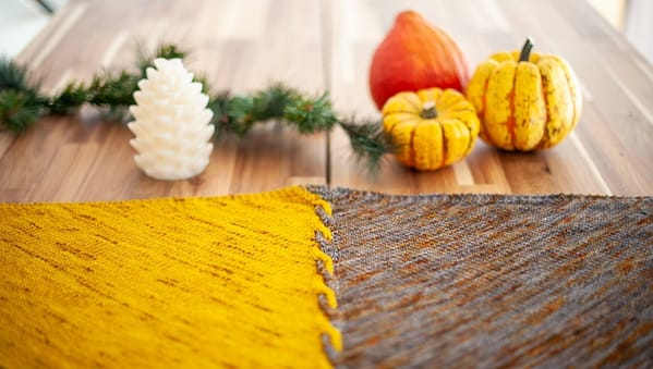 Edge of Winter Shawl laid flat surrounded by some pumpkins for decoration